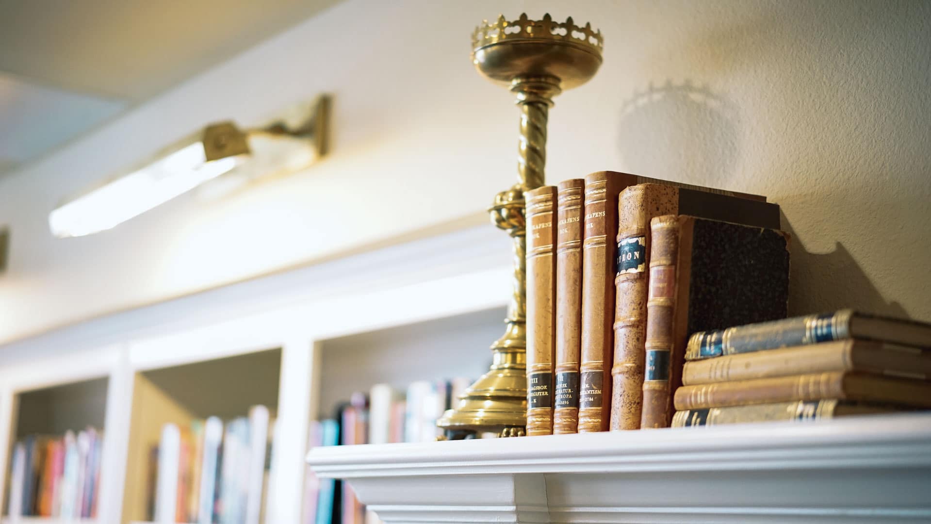 A set of classic books, with a brass candlestick bookstop, in a library at Tradition Senior Living.