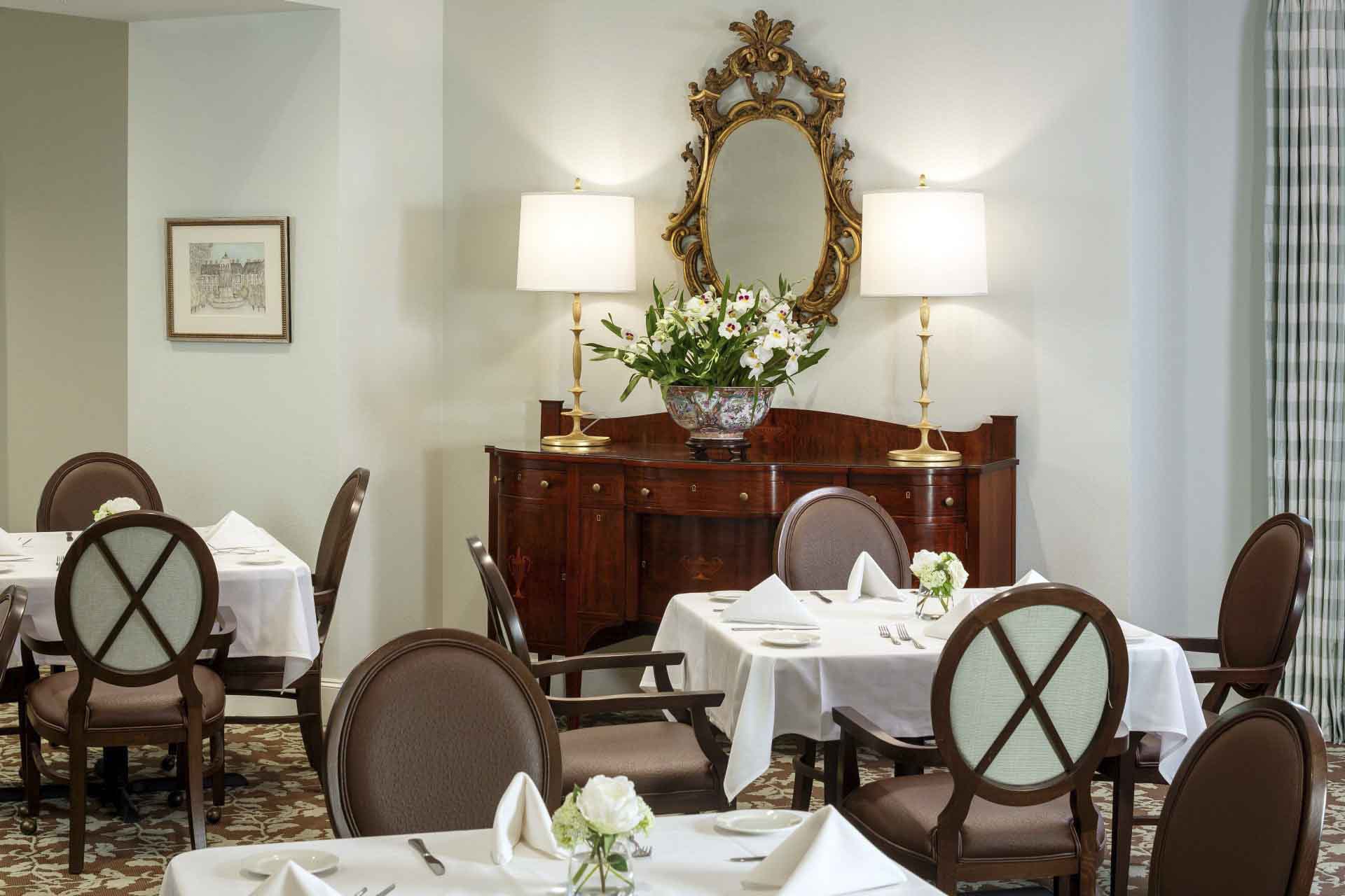 A community dining area, with tablecloths and floral centerpieces, at Tradition Senior Living, in Dallas, Texas.